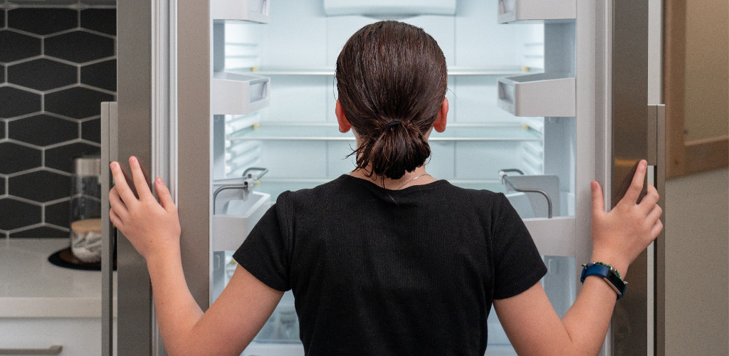 Frau vor leeren Kühlschrank